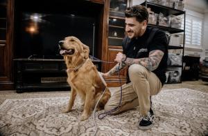 A man kneeling next to his dog while applying PEMF therapy. Picture used by MagnaWavePEMF